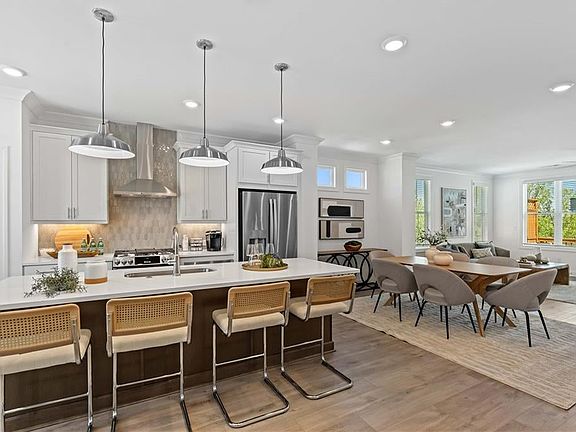 Kitchen featuring wall chimney range hood, stainless steel appliances, light countertops, open floor