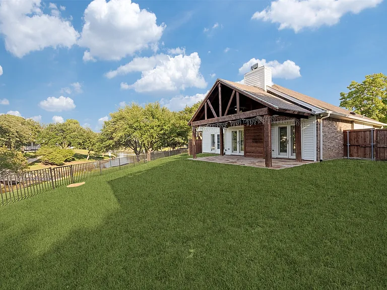 Expansive backyard with a manicured lawn, an outdoor patio featuring a wood-beamed pergola, and multiple double-door access points to the interior