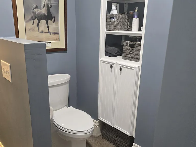 Private water closet with ample storage cabinets.