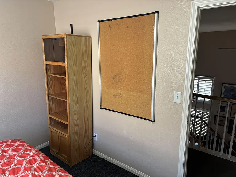 Private bedroom with a bed area, convenient built-in-style shelving, and wall space for a bulletin board or display.