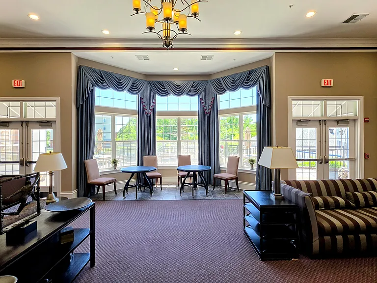 Bright, elegant clubhouse lounge featuring sweeping bay windows, premium drapery, and comfortable conversational seating.