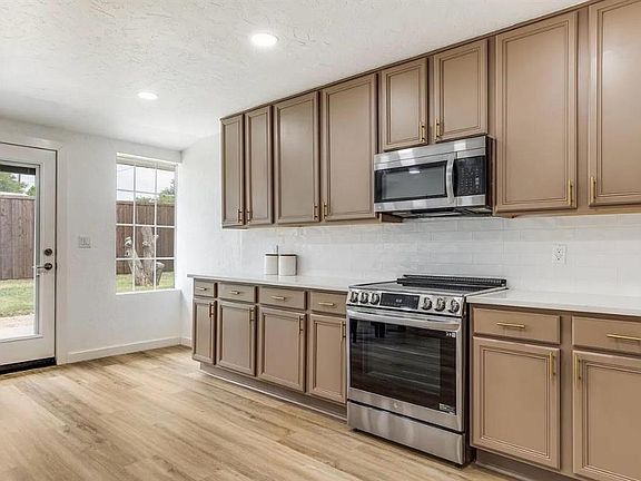 Kitchen with stainless steel appliances, tasteful backsplash, light wood-style flooring, recessed lighting, and light stone countertops
