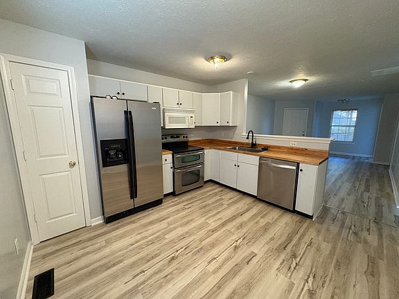 Totally updated kitchen with stainless steel appliances including refrigerator, electric oven/range, and microwave, new bucher block counters as well as all new flooring