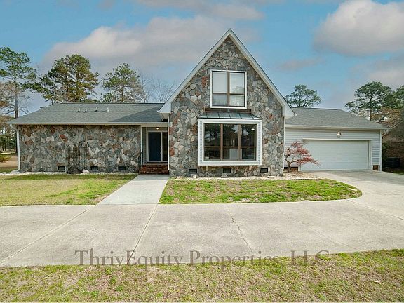 Striking A-frame architecture and stone facade with 2-car garage and wide driveway.