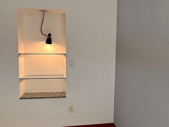 Built-in glass shelving with light in main living area. polished concrete floor.