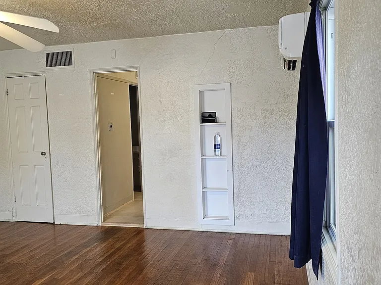 Living room from the front door. Closet is on the left kitchen in the middle. small shelf to right.