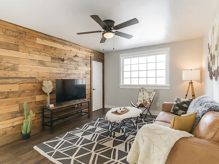 This cozy living room features a warm wood accent wall, leather sofa, and all the comforts you need for a relaxing night in.