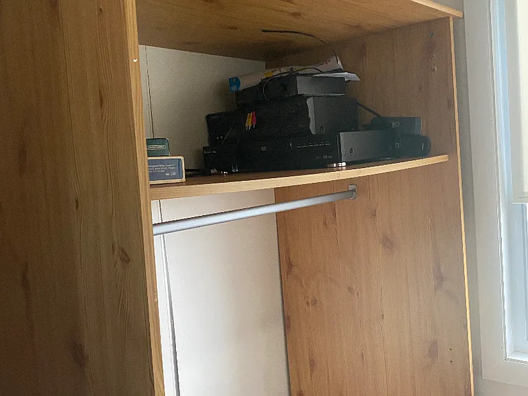 Armoire : rack for hanging clothes and shelf for extras.