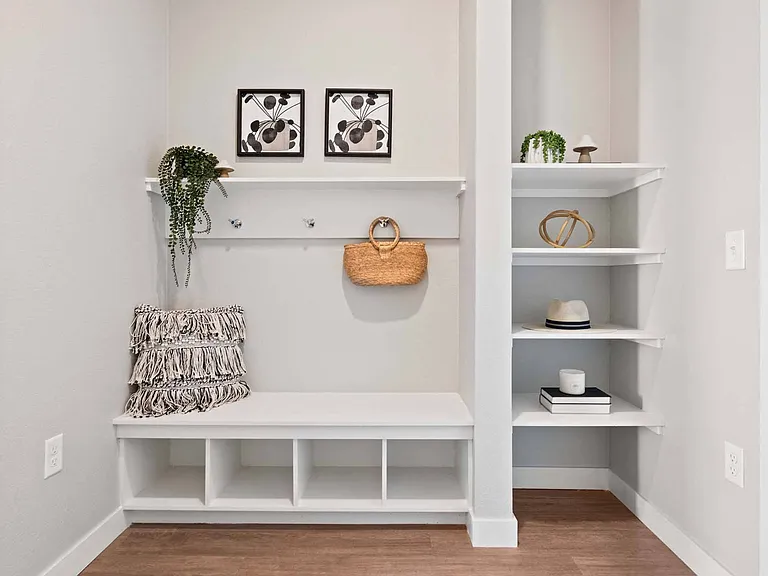 Step into a welcoming entryway featuring a white bench and stylish shelves.