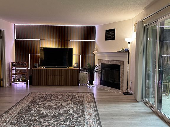 Living Area; Beautiful wood panel wall with smart lighting installed that elevates the space and comfort. Staged to showcase multiple furniture arrangements and flexible use of space.