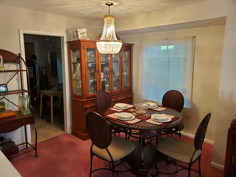 Dedicated dining area with a chandelier, round table seating, and a large window for natural light.
