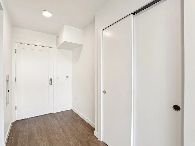 Discover modern living at 4400 Alaska in Seattle, WA. This apartment entryway features sleek wood-look flooring and convenient sliding closet storage.