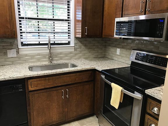 Stainless steel oven with glass electric stovetop. Microwave over stove in kitchen