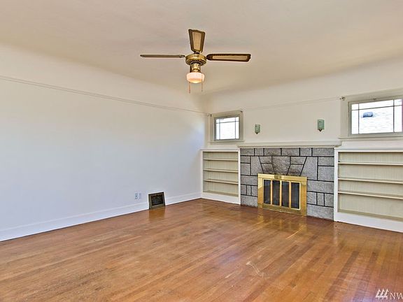 The spacious living room features a original hardwoods, woodburning fireplace, coved ceilings and darling bookends. 