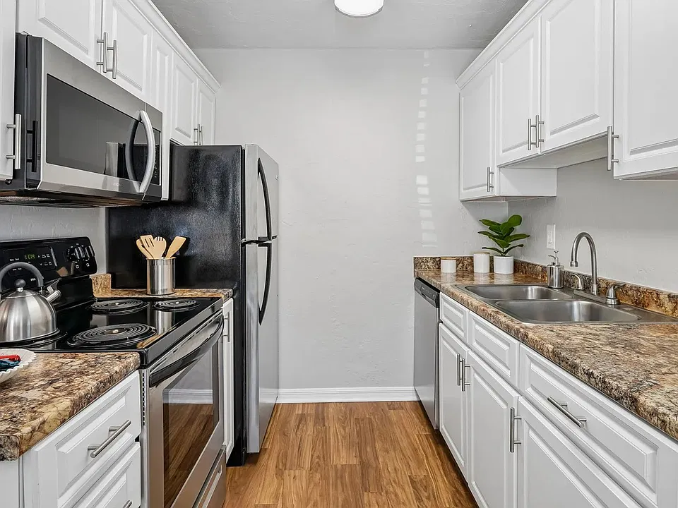 Galley-style kitchen featuring white shaker-style cabinetry, granite-inspired countertops, ample cabinet storage, and a functional layout.