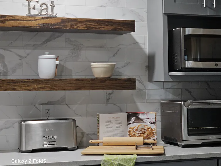 A full height ceramic backsplash with custom floating shelves gives the kitchen a timeless and modern look.