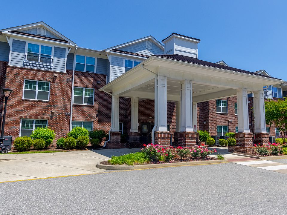 Beautifully maintained front entry with brick facade, manicured shrubs, and architectural portico at Snowden Senior Apartments.