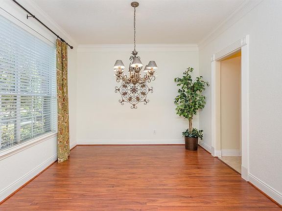 The dining room offers a double wide window with views of the pretty front landscaping and lawn and boasts crown molding and decorative molding around the door that leads to the kitchen area. Notice the pretty decorative metal and crystal chandelier.