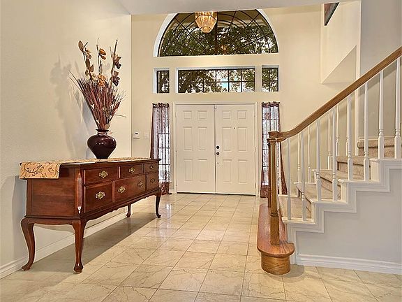 Large welcoming entry with double doors and marble flooring.