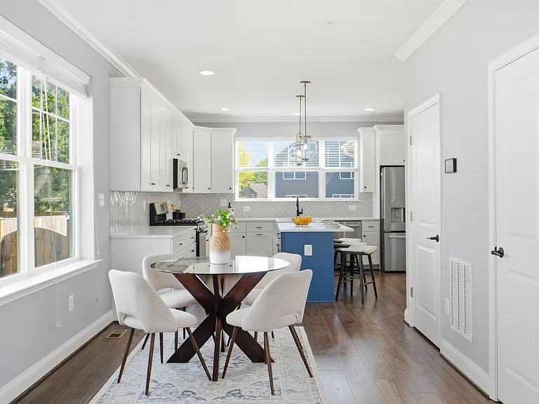 Chef's kitchen with island, farmhouse sink, herringbone backsplash, gas range, and breakfast nook.
