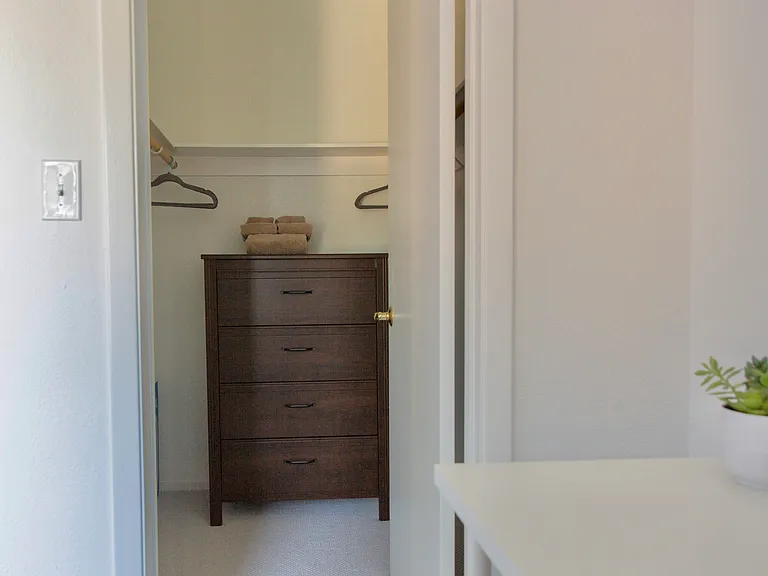2nd bedroom walk in closet with dresser, hangers, set of thick towels, hamper and 2nd set of full sheets.