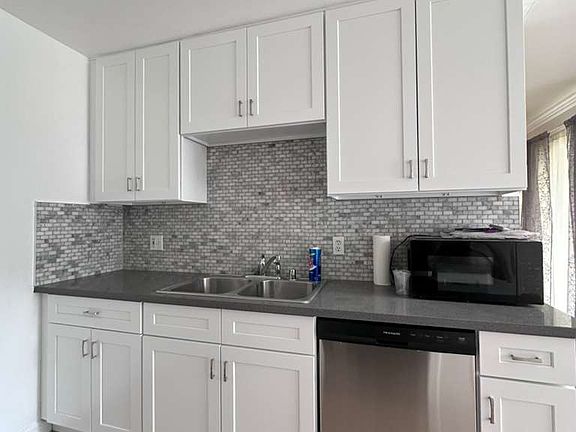 Enjoy cooking in this beautifully updated kitchen, featuring brand new, just-installed white cabinets and a brand new dishwasher. The modern look is completed with new grey countertops and a stylish tile backsplash.