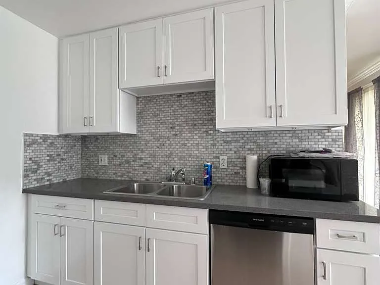 Enjoy cooking in this beautifully updated kitchen, featuring brand new, just-installed white cabinets and a brand new dishwasher. The modern look is completed with new grey countertops and a stylish tile backsplash.