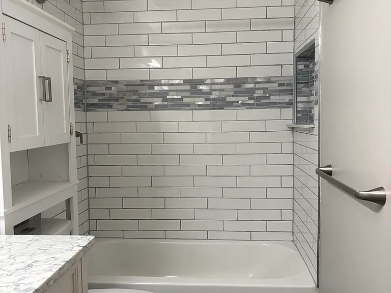 Larger format subway tile carries to the ceiling. Curved shower rod. Built-in shower niche