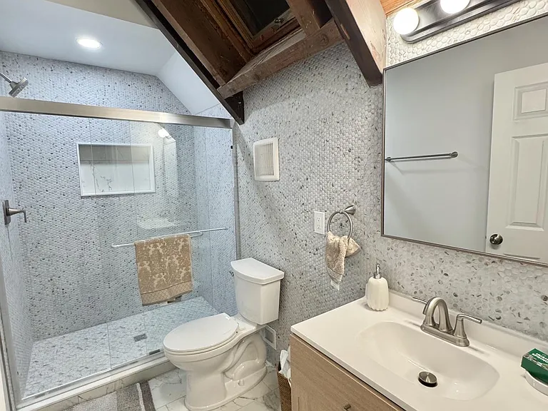 Stylish bathroom with a glass-enclosed walk-in shower, large vanity, and updated tile finishes for easy upkeep.