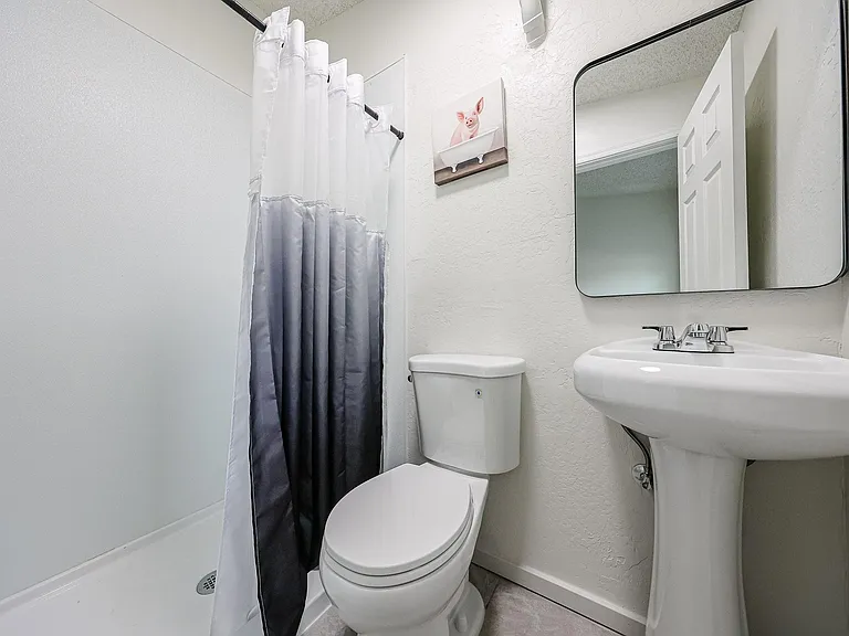 Well-kept full bath with tub/shower combo, pedestal sink, and wall mirror for easy daily routines.