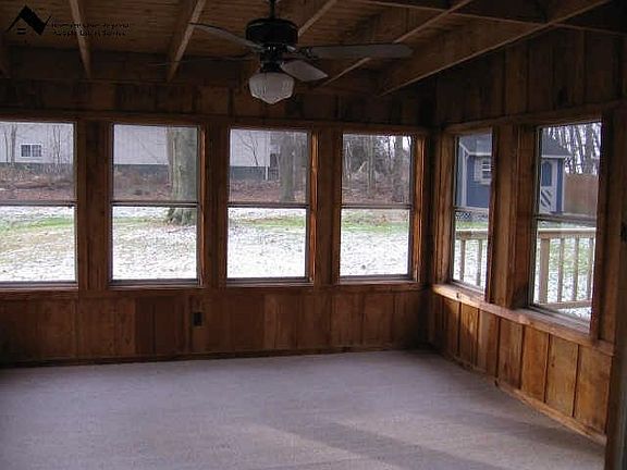 3 season Florida room with ceiling fan and peaceful view of back yard.