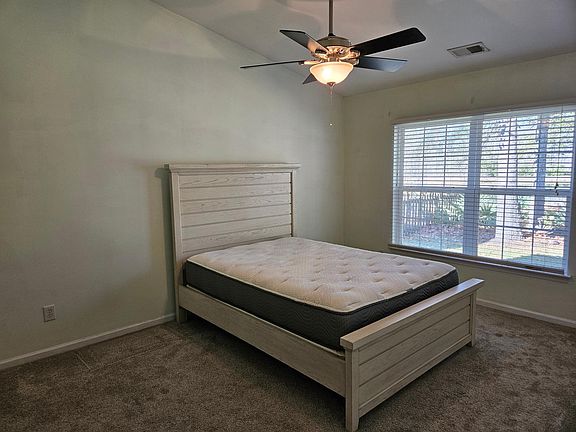 Master bedroom (queen bed for spatial context only) at the back of the house, facing pond. Walk-in closet.