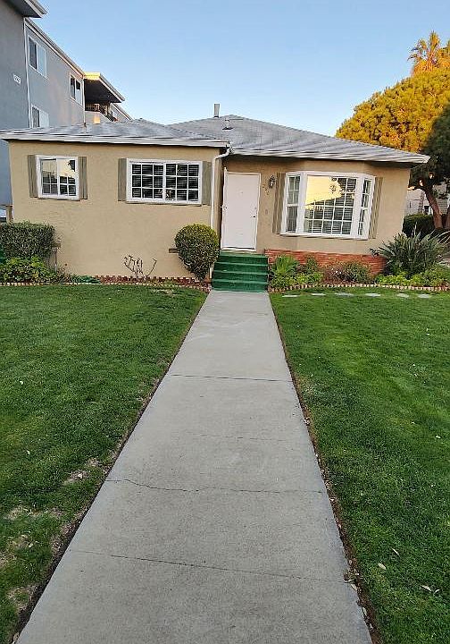 Sidewalk to front door with lawn and bay window.