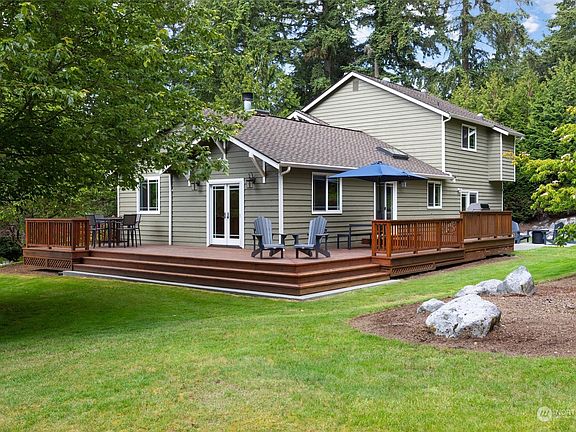 Pic from the back yard showing the wrap-around deck.  Roof is in great shape and has debris screens on the gutters.>