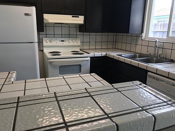 Kitchen with refrigerator, electric stove/oven, dual stainless steel kitchen sink, pot-style faucet, dual paned window, dishwasher, island workstation/breakfast bar, and new paint