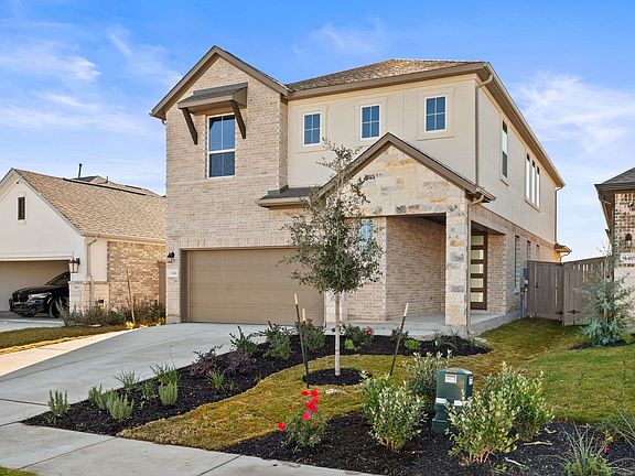 A two-story residential house with a brick exterior, surrounded by a well-maintained landscaped yard