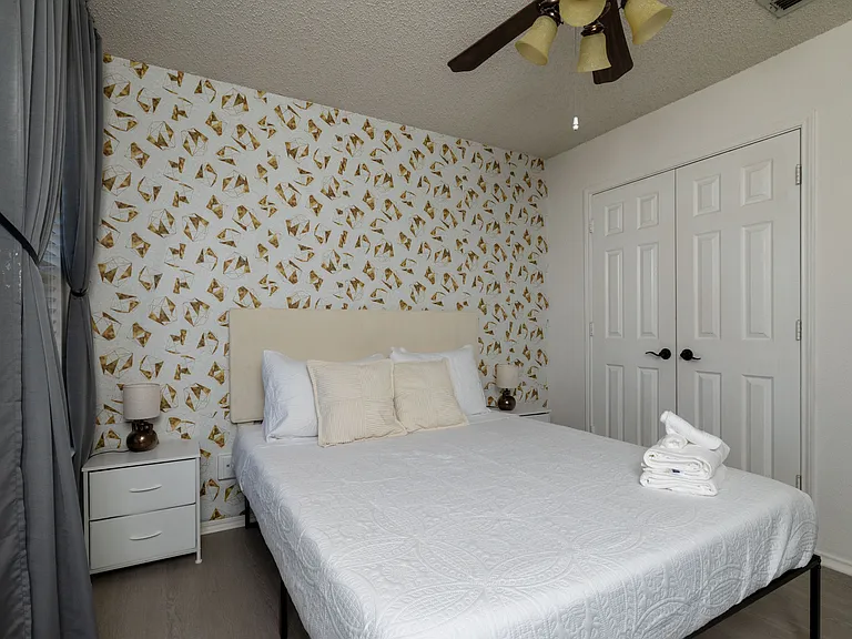Bright bedroom with a stylish butterfly accent wall and queen-size bed.