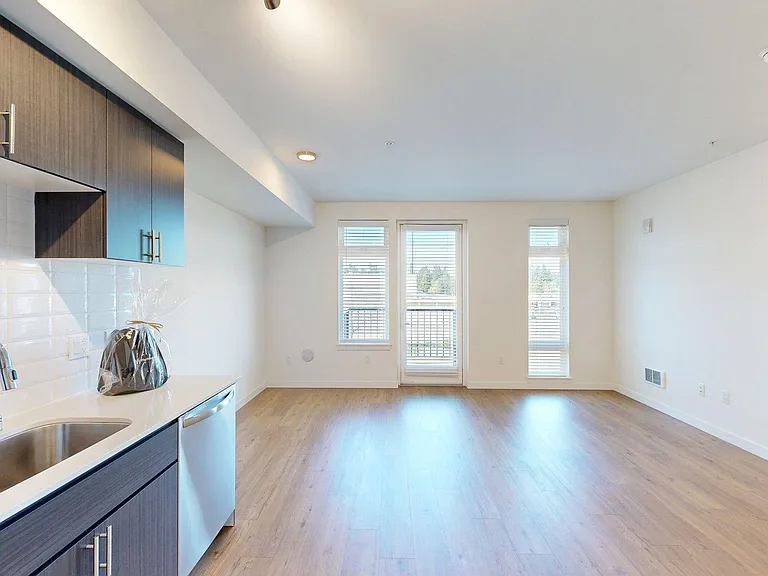 Apartment Kitchen with Stainless Steel Appliances, Dining and Living Room with Wood-Style Flooring.
