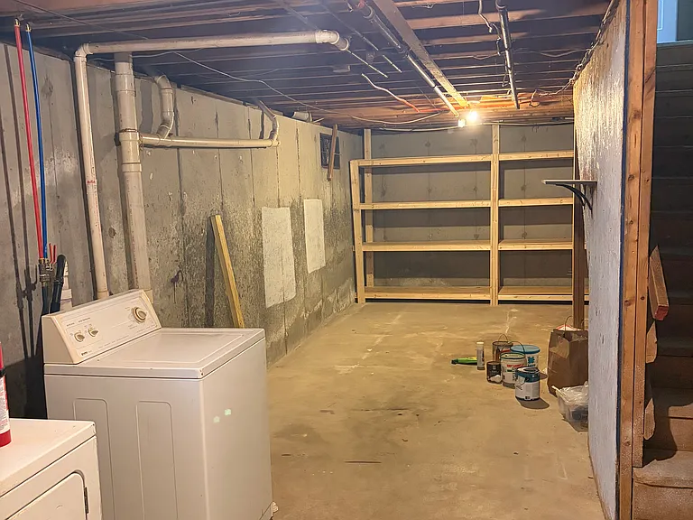 Basement with ample storage space, built-in storage shelving, and in-unit washer and dryer.