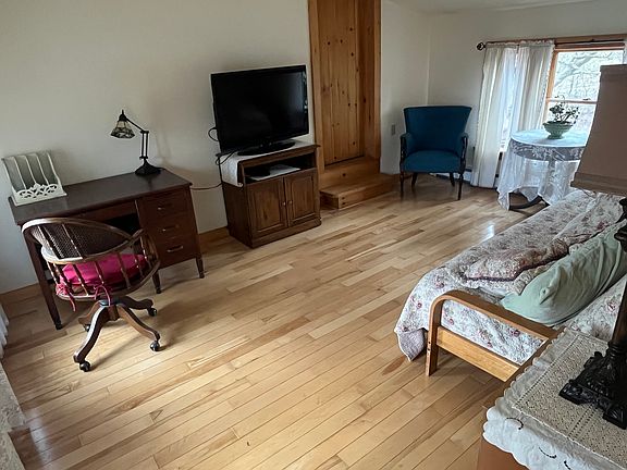 Living room with some stained glass lighting, a desk, flat screen with streaming service, double futon with cotton and foam layers to sleep 2 guests.