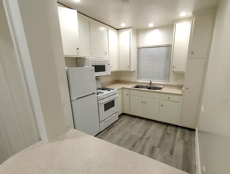 nice size kitchen, refrigerator and microwave with a bar table top to set up stools for eating and serving food