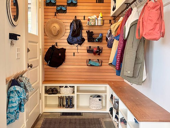 The entryway includes a custom slatwall and cabinets for ample and versatile storage.