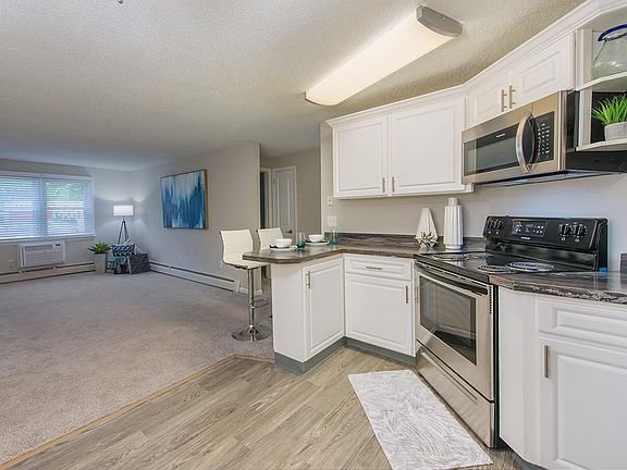 Updated kitchens with black fusion counter tops, wood-style flooring, and stainless steel appliances.