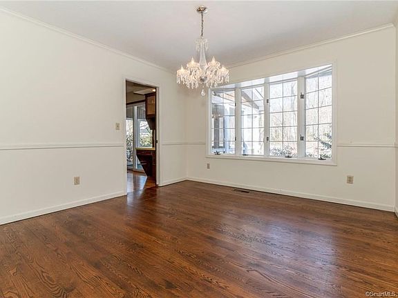Elegant dining room distinguished with such high-end finishes such as chair rail molding and crown molding. Also note the large bay window at the far side of the room and the beautiful hardwood flooring. (The chandelier is excluded from this listing and does not convey with the house.)