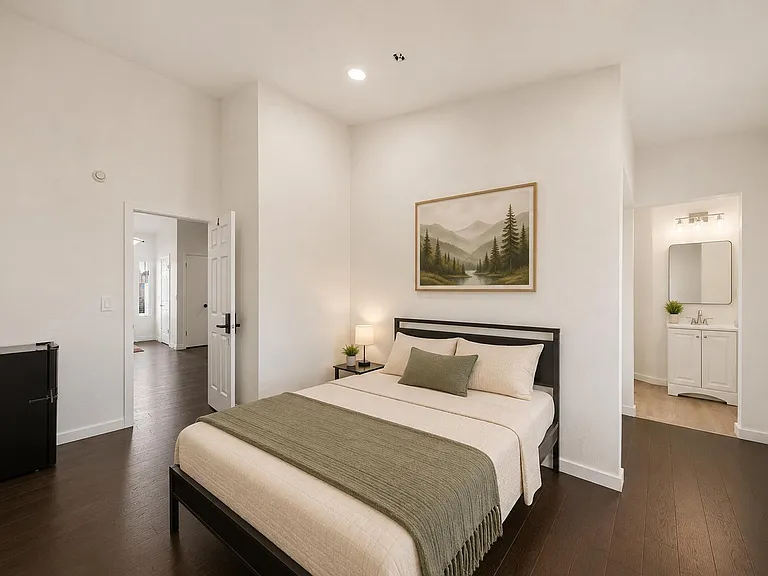 Spacious bedroom with high ceilings, hardwood floors, and a private vanity area plus mini fridge for added convenience.