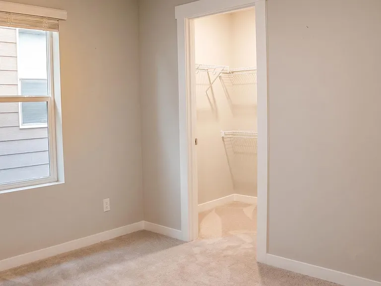Unfurnished bedroom with carpet flooring, a window for natural light, and an open closet with wire shelving for storage.