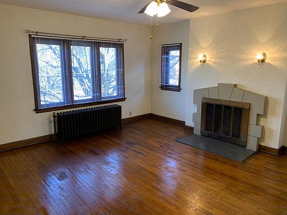 Living room with wood burning fireplace and ceiling fan.