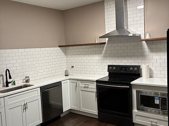 Renovated kitchen with quartz countertops, newer microwave, dishwasher, vent hood, sink and shelving. Refrigerator and stove included.