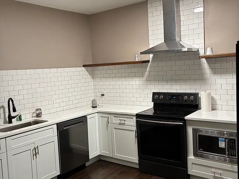 Renovated kitchen with quartz countertops, newer microwave, dishwasher, vent hood, sink and shelving. Refrigerator and stove included.