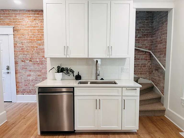 Dishwasher and exposed brick with door to attached garage.